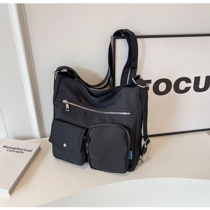 Detail view of large nylon crossbody bag showing multiple pockets and adjustable strap