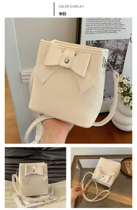 Detail of a creamy white bucket bag with a large decorative bow and adjustable strap