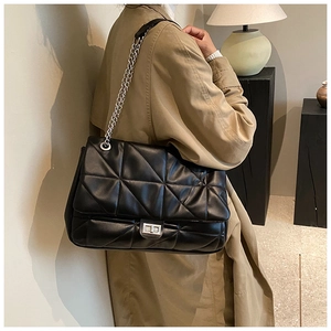 Detail of black quilted leather shoulder bag with silver chain and metal turn-lock