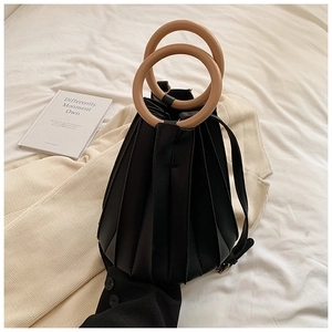 Détail du sac seau plissé noir avec poignées en anneaux de bois sur maille douce