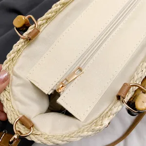 Detail view of woven straw bag with smooth metal zipper, canvas lining, and bamboo buckle