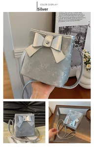 Detail of silver bow bucket bag showing matte metallic texture and adjustable strap