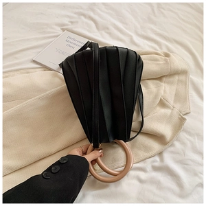 Détail du sac plissé noir avec de grandes poignées circulaires de couleur kaki clair