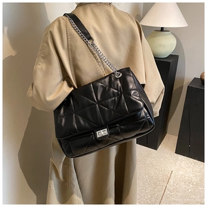 Detail of black quilted leather shoulder bag with silver twist lock and chain strap