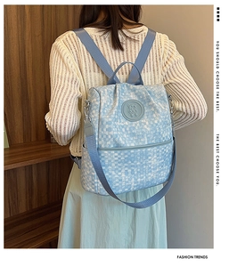 Détail du motif tressé à carreaux bleu et blanc avec logo ours gravé sur le sac à dos
