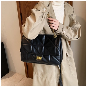 Detail of black quilted shoulder bag featuring gold chain strap and metal swivel lock