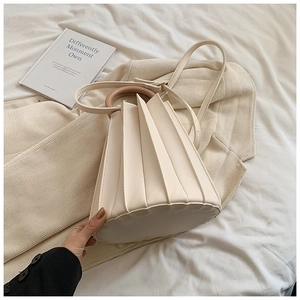 Détail du sac seau plissé crème avec poignées rondes en bois et bandoulière réglable