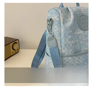 Détail du sac à dos à carreaux bleus et blancs avec crochets métalliques et logo ours