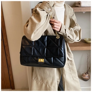 Close-up of black quilted shoulder bag with gold chain strap and turn-lock closure