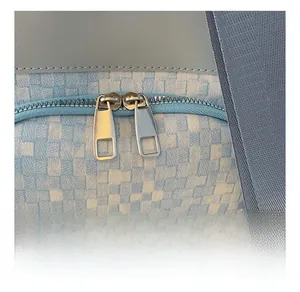 Détail des doubles fermetures éclair en métal sur un sac à dos tissé bleu et beige poli