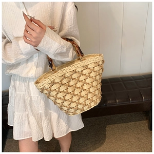 Detail of woven straw handbag with tortoise shell resin handle and inner lining