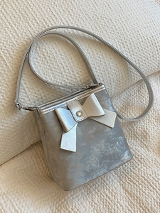 Silver metallic bow bucket bag with textured synthetic leather and slim shoulder strap