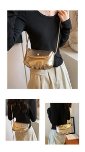 Detail of golden pleated cloud bag featuring glossy metallic finish and slim chain strap