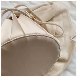 Détail du sac seau plissé crème montrant les coutures précises et la boucle dorée en métal
