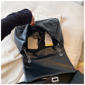 Detail shot of black quilted shoulder bag interior showing spacious capacity and silver chain