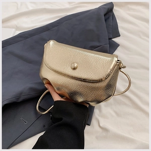 Detailed view of golden metallic litchi grain texture on crossbody cloud bag