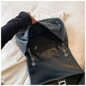 Top view of black quilted leather bag interior featuring a silver zipper pocket and chain