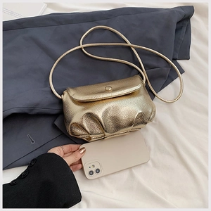 Detailed view of champagne gold pleated cloud bag showing mini size relative to a phone