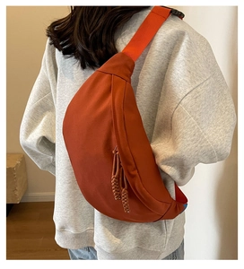Détail du sac bandoulière rouge rouille en toile avec texture et zip tressé élégant