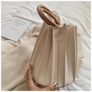 Détail du sac seau plissé beige avec doubles poignées anneaux marron sur fond en tissu