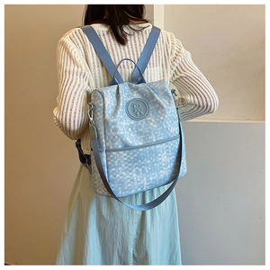 Détail d'un sac à dos à carreaux bleu clair avec logo ours et bretelles réglables