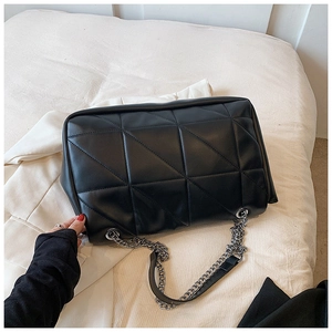 Detailed shot of black quilted shoulder bag with large triangle pattern and silver chain