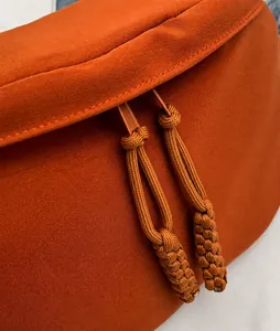 Détail du sac en toile orange avec doubles fermetures éclair et tirettes en corde tressée