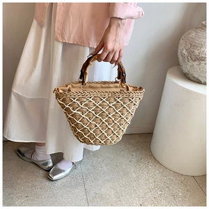 Detail of woven straw bag with white lattice pattern and vintage bamboo handle texture