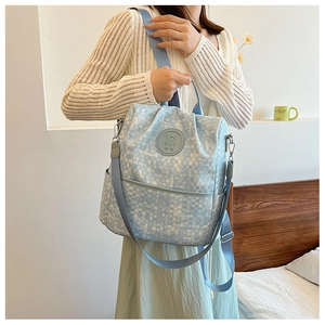 Détail latéral du sac à dos bleu clair à motif pixel avec badge ours et poche latérale