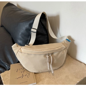 Détail du sac croissant beige en toile avec tirettes tressées et bandoulière large