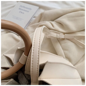 Détail du sac plissé crème avec poignée ronde rigide et fine bandoulière réglable