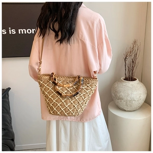 Detail of woven straw tote bag with bamboo handles and grid pattern on a model