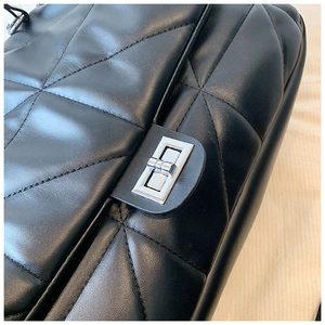 Close-up of black quilted leather texture and silver rectangular twist lock closure
