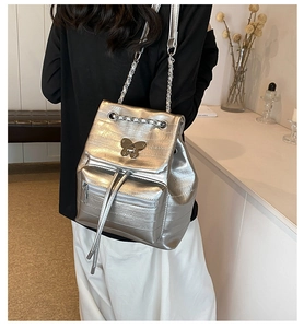 Detailed view of silver metallic backpack with quilted texture and butterfly buckle
