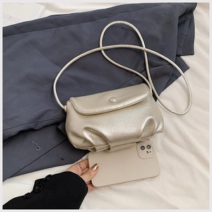 Mini silver pleated cloud bag detail showing compact size compared to a smartphone