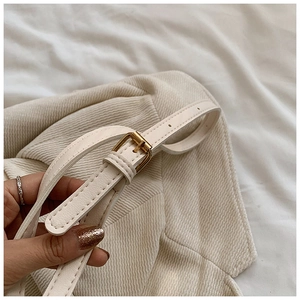 Détail du tissu en velours côtelé crème avec boucle en métal doré et sangle en similicuir
