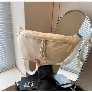 Détail du sac demi-lune beige en nylon avec zips tressés et large bandoulière toile