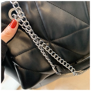 Detail of black quilted leather shoulder bag with silver chain strap and metal eyelets