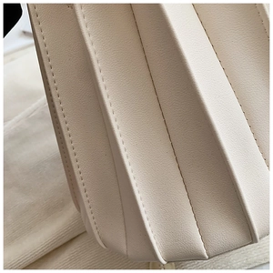 Détail de sac seau plissé blanc crème montrant la texture du cuir à grain de litchi premium