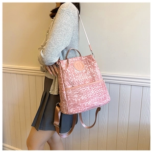 Détail macro du motif à damier rose et du logo d'ours mignon sur le sac à dos
