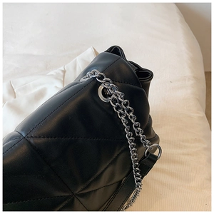 Detail of black quilted leather shoulder bag with polished silver metal chain strap