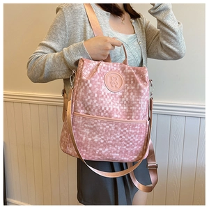Détail du sac à dos à carreaux roses avec logo ours et texture de tissu tissé