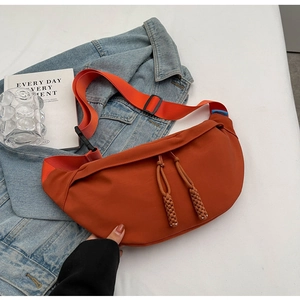 Détail du sac croissant en nylon orange avec cordes tressées sur veste en jean