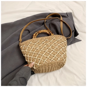 Detailed close-up of woven straw bag with bamboo handles and chic leather shoulder strap