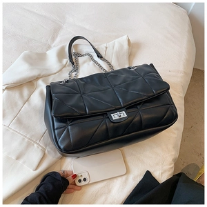 Detailed view of black quilted shoulder bag with silver chain strap and metal clasp closure