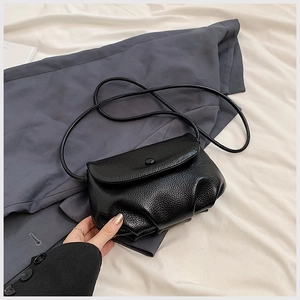 Detail of black pebbled leather cloud bag with pleated texture and snap closure
