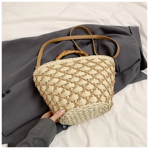Detail of woven straw handbag featuring vintage bamboo handles and brown leather strap