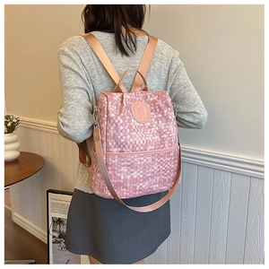Détail du sac à dos rose à texture tissée avec écusson ours et poignée supérieure