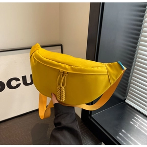 Détail du sac banane jaune en toile avec des tirettes de fermeture à pompons tressés