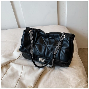 Detail of black quilted leather shoulder bag with silver chain strap and metal clasp